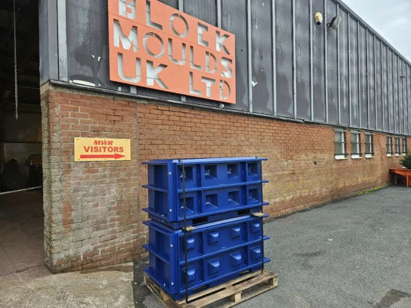 Blue interlocking block moulds stacked on a pallet outside the Millom works