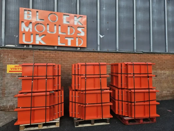 Three stacks of orange interlocking block moulds outside the Block Moulds UK Ltd works in Millom