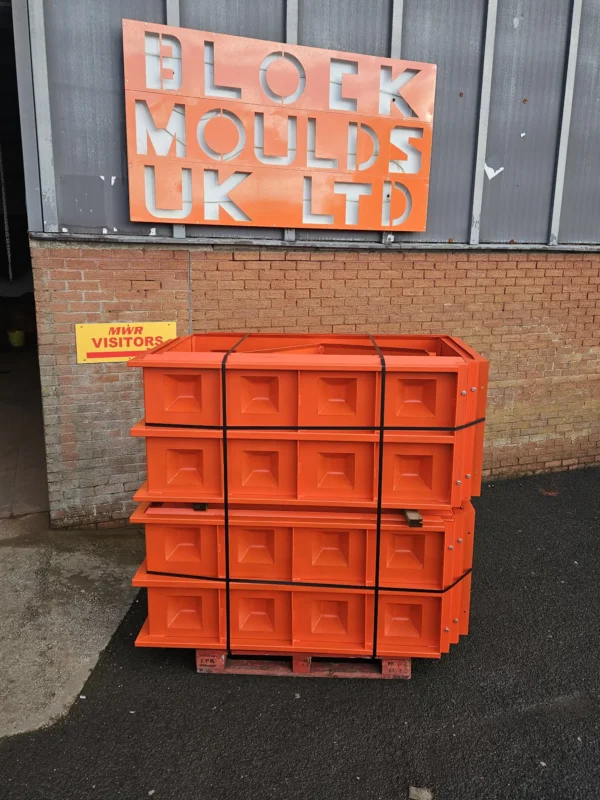 Stacked orange concrete block moulds on a pallet at Block Moulds UK Ltd